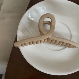 Detail einer matt beigen Haarklammer im minimalistischen, gedrehten Schlaufendesign