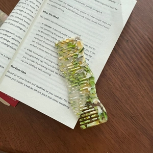 Detail of French wavy acetate hair comb with green and yellow marble texture on book