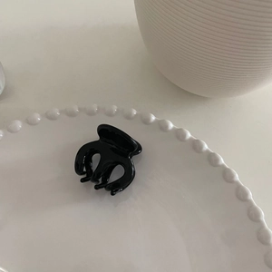 Detailansicht einer glänzenden schwarzen Haarklammer aus Acetat auf einem weißen Keramikteller