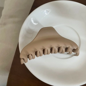 Detailansicht der großen matten Haarklammer in Beige auf weißem Keramikteller