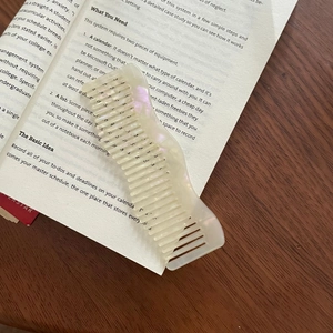 French wavy hair comb with cream pearlescent finish on vintage book background