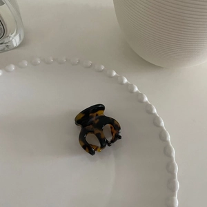 Nahaufnahme der Mini-Haarklammer mit Schildpatt-Muster auf weißem Dekoteller