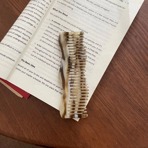 Close-up of a French wavy acetate hair claw clip with tortoise shell pattern on a book