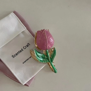 Elegant tulip claw clip in pink enamel and gold metal on a white fabric background