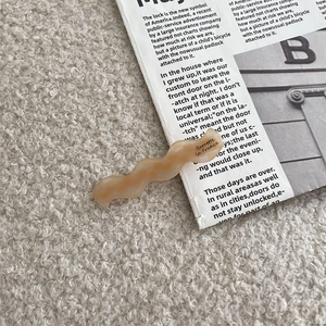 Détail d'une pince à cheveux en acétate champagne avec texture marbrée et texte