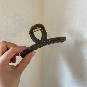 Detailed close-up of dark brown acrylic hair claw clip with a glossy finish and metal spring