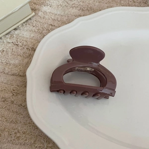 Pince à cheveux en acétate marron moka avec logo Handmade sur une assiette en céramique