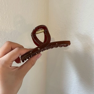 Glossy amber acrylic shark hair claw clip for women shown in a hand-held view