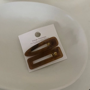 Detail view of retro brown tortoiseshell acetate hair clips set on a white card display