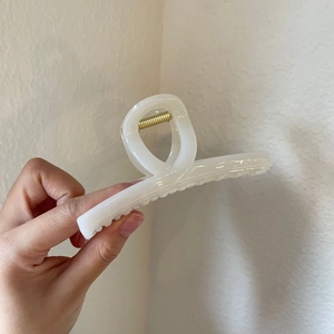Detail of cross-design acrylic hair claw clip in translucent milky white with gold spring
