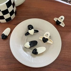Minimalist black and white heart hair clips set displayed on a white ceramic plate