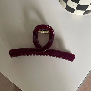 Detail of burgundy large hair claw clip with glossy resin finish and gold metal spring