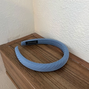 Close-up of light blue fabric headband with diagonal twill texture and handmade label