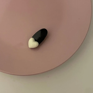 Vintage black and white heart hair clip with heart detail on a minimalist pink display tray