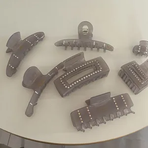 Pinces à cheveux en acétate gris avec strass de formes variées sur une table blanche