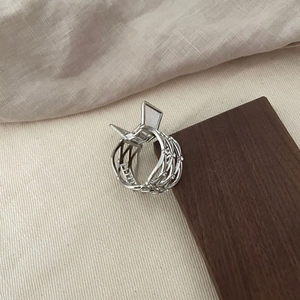 Elegant silver hollow mesh hair claw clip with floral accents on a textured surface
