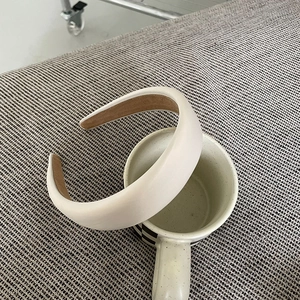 Detail of a padded off-white satin headband featuring brown anti-slip inner lining