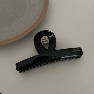Detail of a large black acetate hair claw clip with golden Barrette La France text