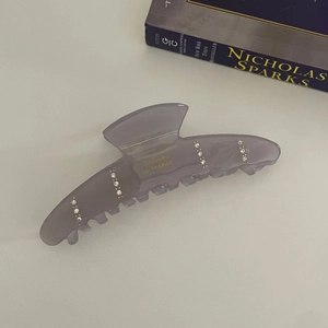 Vue détaillée de la pince à cheveux en acétate avec strass et inscription dorée