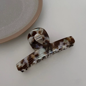 Macro shot of a large acetate hair claw clip featuring brown and lilac marble textures