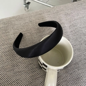 Close-up of a black padded satin headband featuring a smooth finish and a puffy design