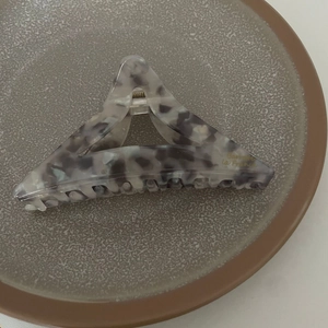 Détail d'une pince à cheveux triangulaire en acétate avec motif marbré et ressort doré