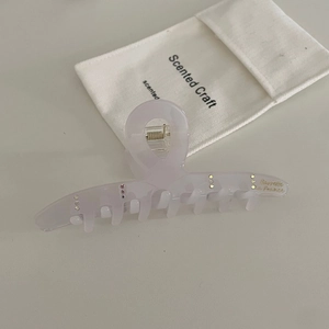 Detail view of pink acetate hair claw with rhinestones and luxury drawstring bag