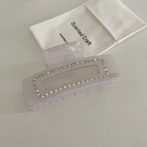 Detail of lavender matte hair claw with crystals and branded drawstring bag
