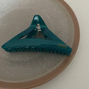 Détail de la pince à cheveux triangle en acétate vert foncé avec lettrage français doré