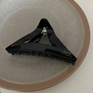 Détail d'une pince à cheveux noire avec logo Barrette la France doré sur coupelle grise