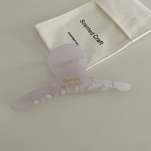 Macro shot of lavender acetate hair claw with gold lettering and rhinestone accents