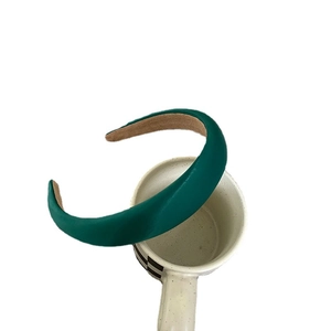 Elegant emerald green satin padded headband displayed on a ceramic mug holder