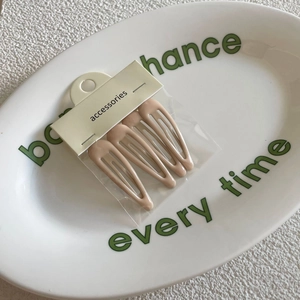 Set of 4 matte beige BB hair clips in cream colors on a white ceramic plate