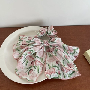 Chouchou en mousseline imprimé tulipes roses avec longs rubans sur plateau blanc