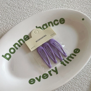 Set of four matte purple teardrop snap clips on a ceramic plate with accessories card