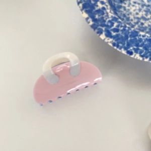 Pink handbag shaped acetate hair claw clip for women on a decorative floral plate