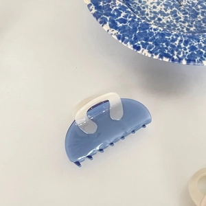 Macro detail of Morandi blue acetate hair claw with elegant marbled texture and creamy white handle
