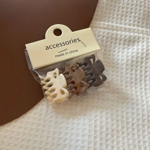 Close-up of three mini matte hair claws in neutral tones with retail card packaging