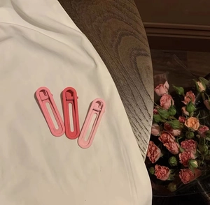 Détail de trois barrettes à cheveux dégradées roses sur un fond en tissu de soie blanc doux