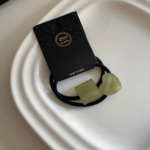 Détail de charms géométriques en acrylique vert sur des élastiques à cheveux noirs