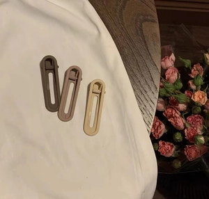 Vue détaillée de trois pinces à cheveux mates aux couleurs Morandi sur tissu en coton