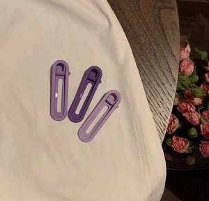Vue détaillée de trois pinces à cheveux sans trace avec dégradé violet sur tissu blanc