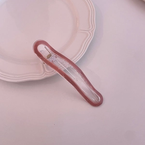 Detailed view of a transparent pink macaron hair clip with a metallic spring mechanism