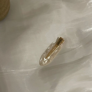 Elegant marble pattern acetate hair clip with golden metal clip on white fabric