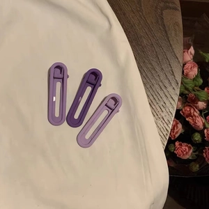 Lot de trois barrettes à dégradé de violet sur tissu blanc et surface en bois