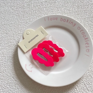 Three-piece cloud-shaped hair clips in hot pink on a display card and ceramic plate
