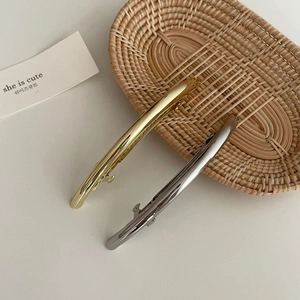Minimalistische Haarspangen aus poliertem Metall in Gold und Silber auf Weidenkorb