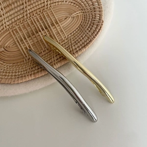 Nahaufnahme minimalistischer Haarspangen aus Gold und Silber mit polierter Oberfläche