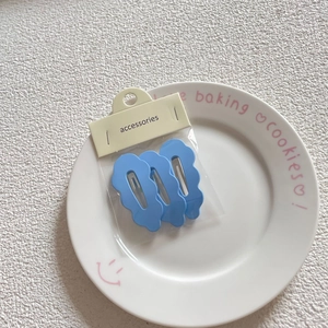 Three blue cloud wave hair clips displayed on a white tray with branded card packaging