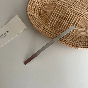 Nahaufnahme einer minimalistischen silbernen Haarspange aus Metall auf einem Rattantablett